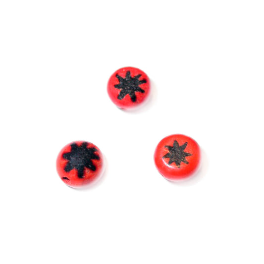 Small red glass bead with black star