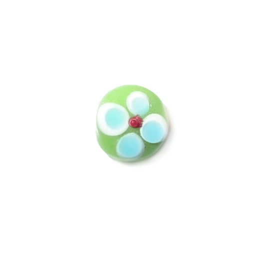 Green, flat glass bead with white, blue and red dots